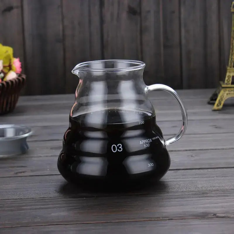 Clear glass coffee kettle with curved handle and measurement markings filled with dark liquid by decorbites cloud shaped
