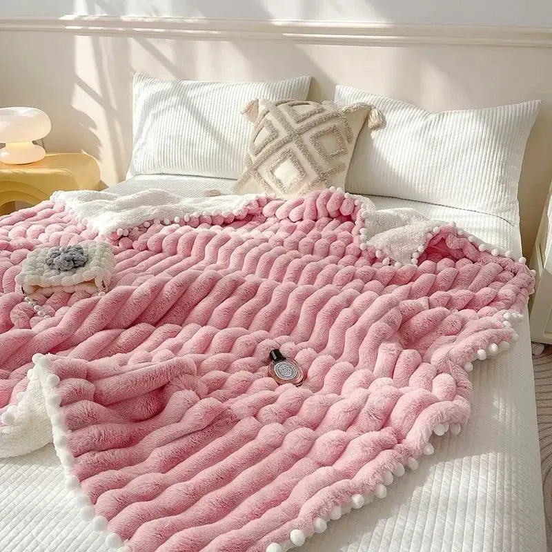 Pink chunky knit throw blanket with white pom-pom trim and plush faux rabbit fur for cozy bed warmth by decorbites