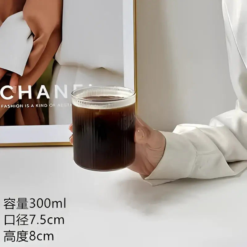 Clear glass cafe coffee tumbler with vertical ridges filled with dark iced coffee by decorbites glass cafe