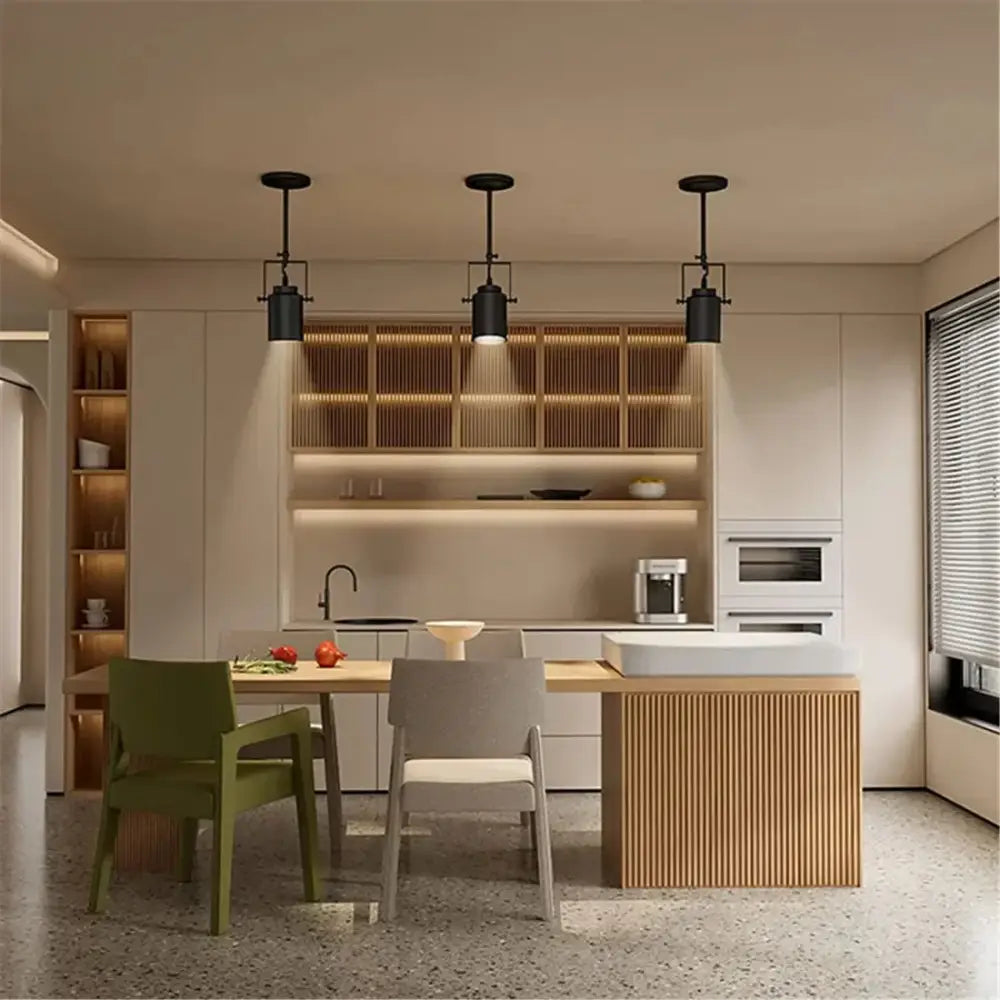 Three black industrial vintage adjustable ceiling lamps hang above a modern kitchen island for decorbites industrial vintage decor