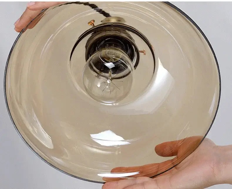 Translucent amber glass pendant light with brass-finished metal base and exposed bulb for dining room use