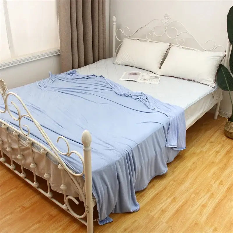 Light blue satin cool feel summer blanket draped over white wrought iron bed frame for decorbites cool feel bedding