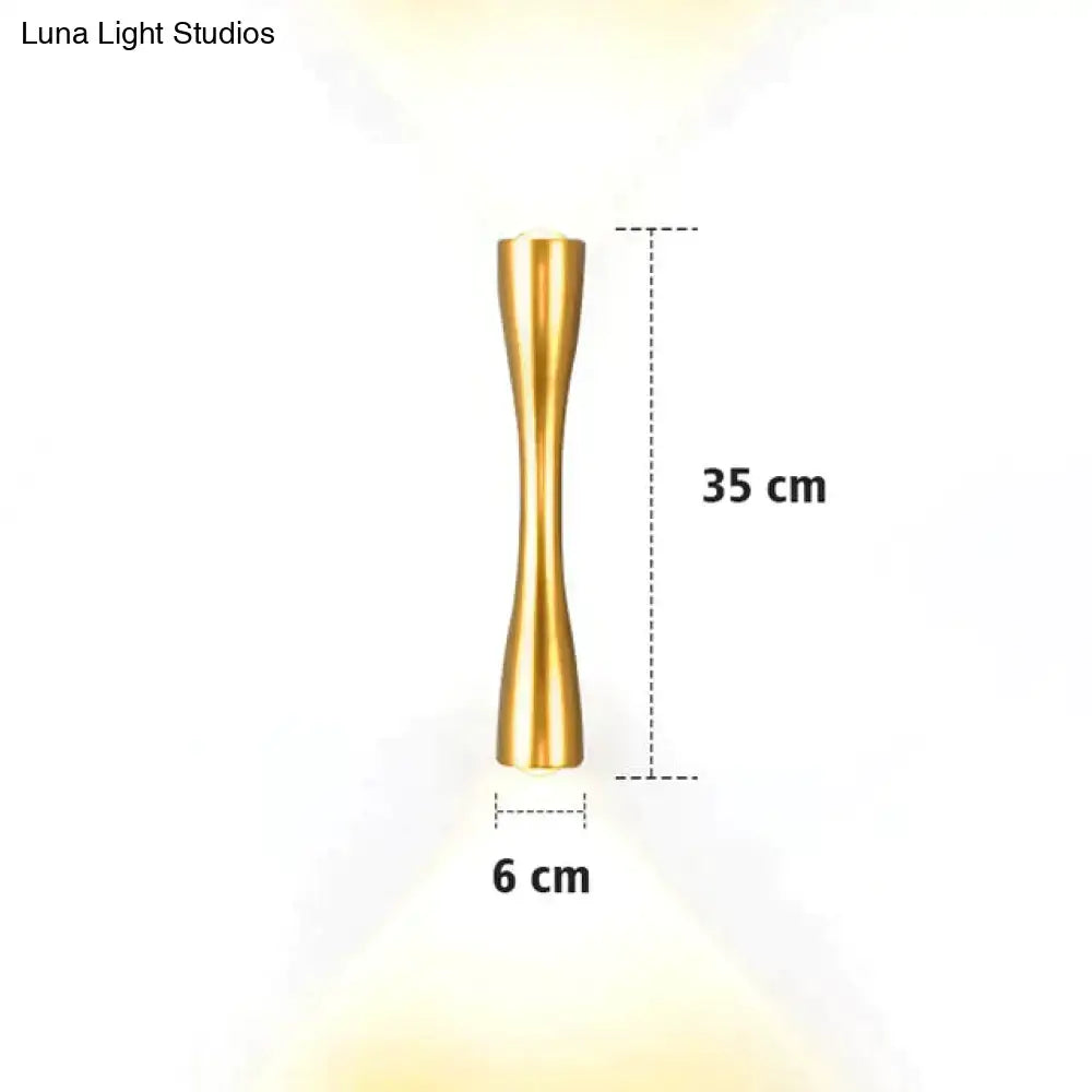 A sleek gold-toned metal wall sconce 35 cm tall with slender hourglass design for modern black curved outdoor porch lighting