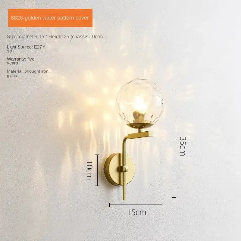Gold-toned wall lamp with decorbites glass ball led globe and black wrought iron arm for modern bedroom sconce decor