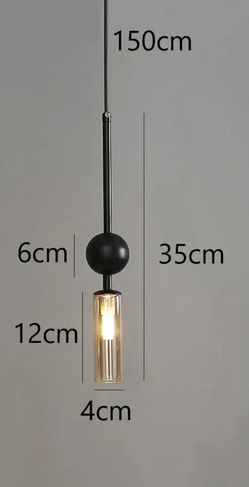 Modern brass and black glass cord pendant light with cylindrical shade and warm led bulb glow for dining room use