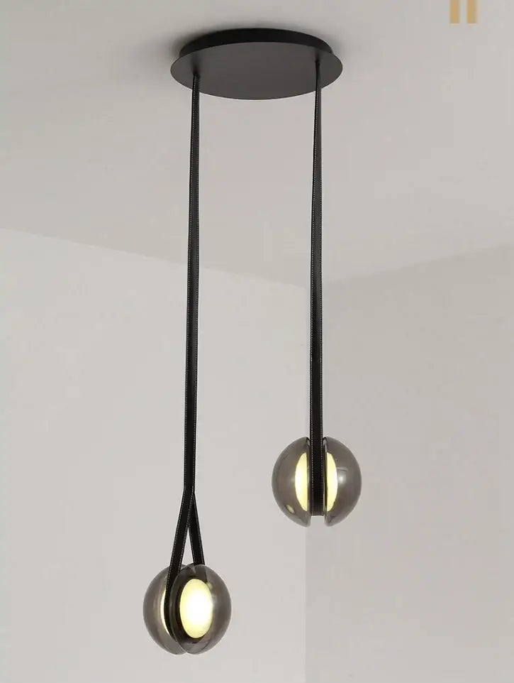 Modern clear glass designer pendant lights with sleek black spherical shades and minimalist metal chains for bedroom decorbites designer pendant lights