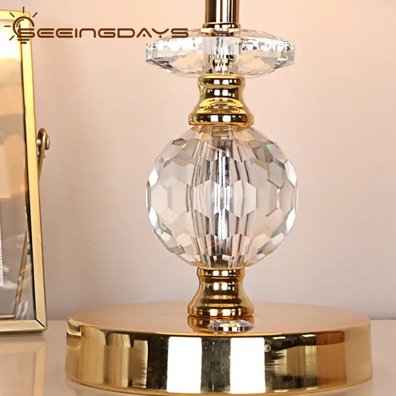 Modern gold crystal ball table lamp with clear faceted crystal and gold metal accents on a round base for bedroom use