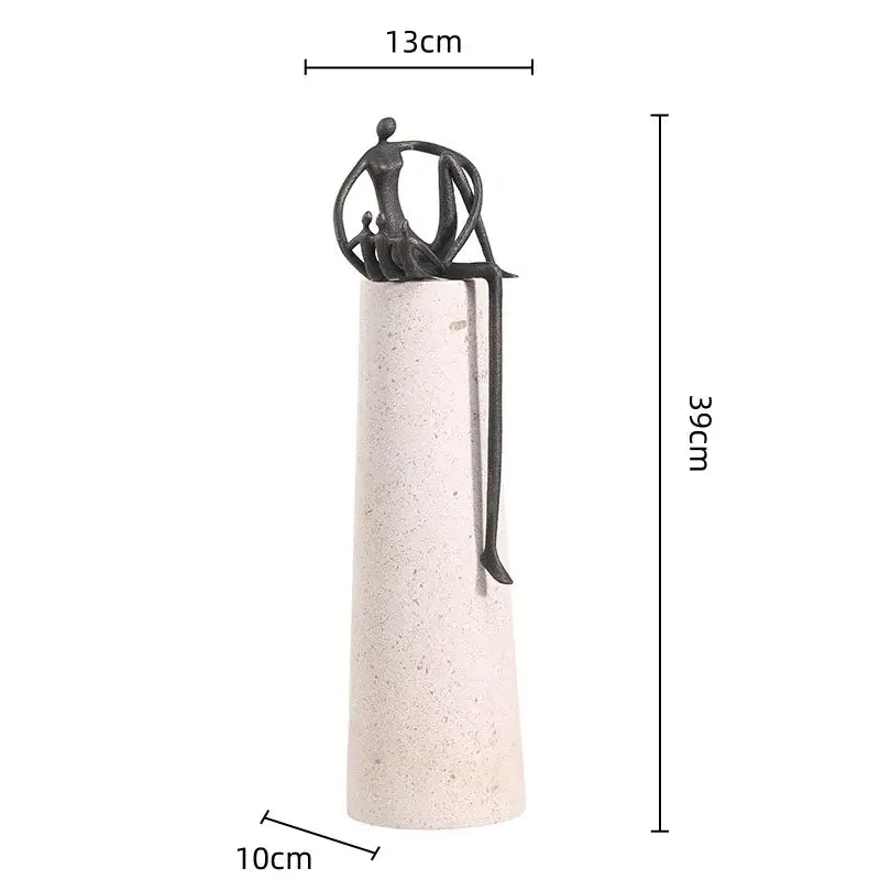 A sleek black metal abstract figure sculpture with intertwined limbs on a textured off-white concrete pedestal decorbites golden metal decor