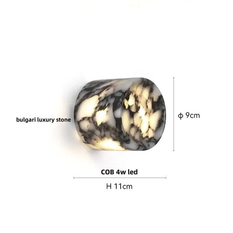 A modern wabi sabi black and cream resin led wall lamp featuring a cylindrical bulgari luxury stone design with a 4w cob led light