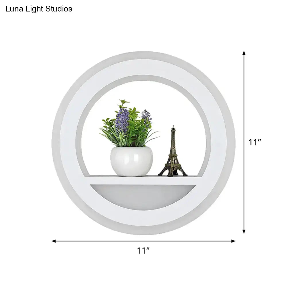 Modern white halo ring wall light fixture with glossy circular shelf holding purple flowers and eiffel tower figurine
