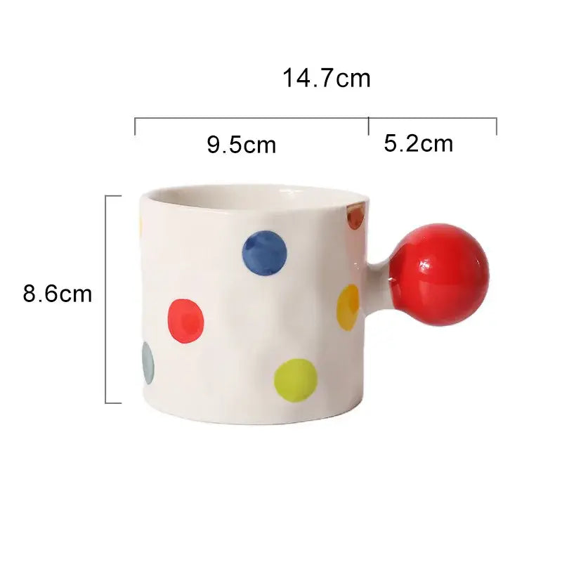 A white ceramic heart design mug with colorful polka dots and a bright red spherical handle for kitchen use