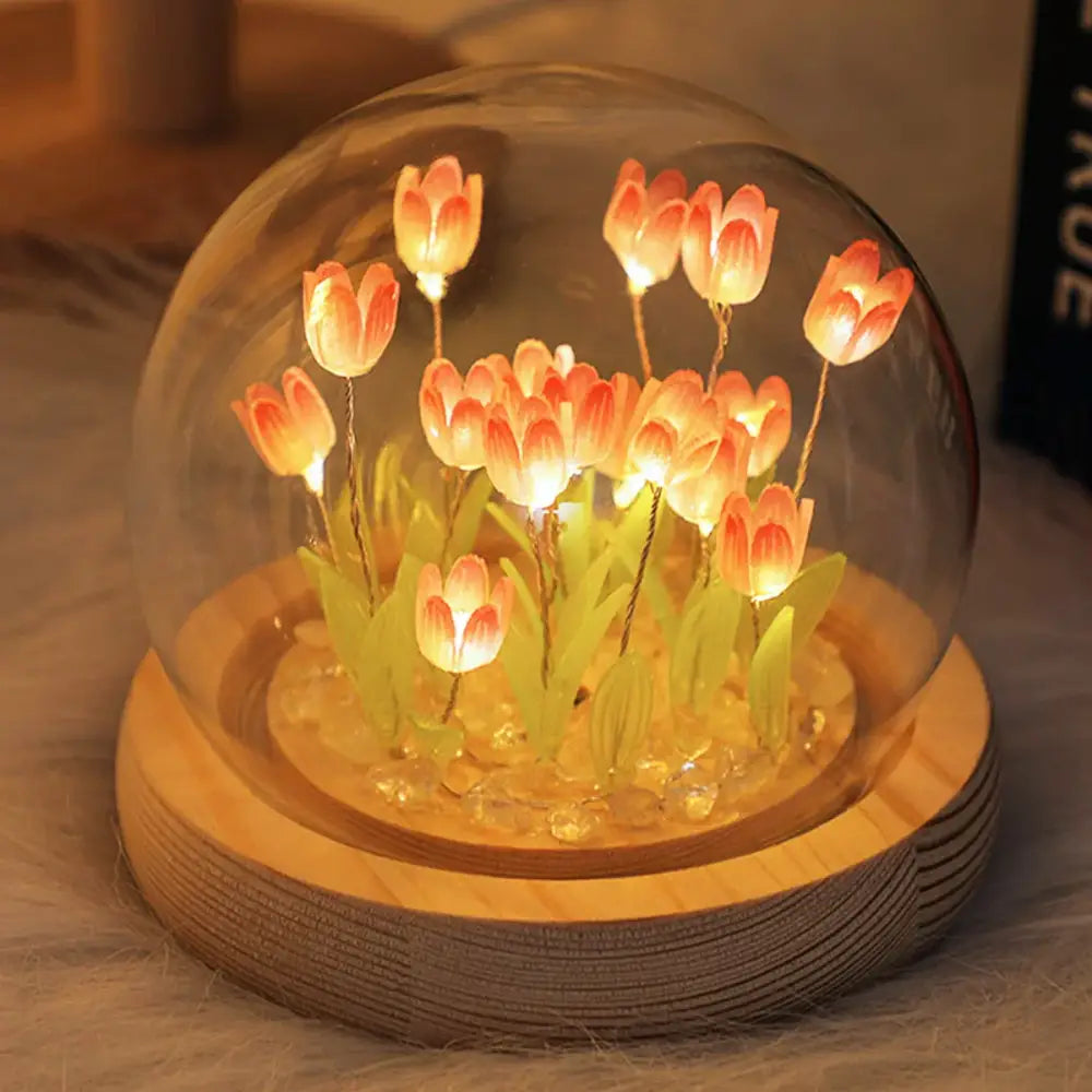A warm glowing tulip night light featuring a miniature tulip garden in a glass dome on a rustic wooden base