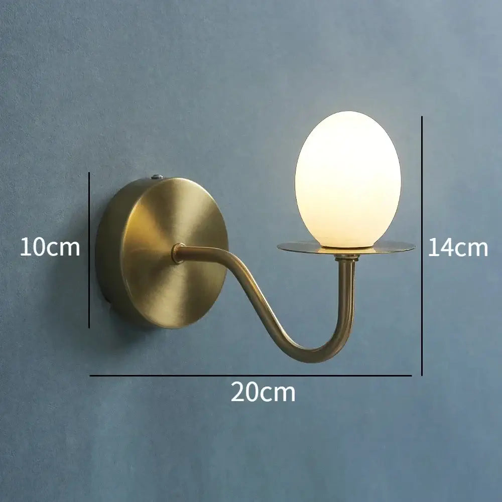 Vintage brass glass egg mini wall lamp with a curved arm and frosted oval bulb ideal for bedroom sconce lighting