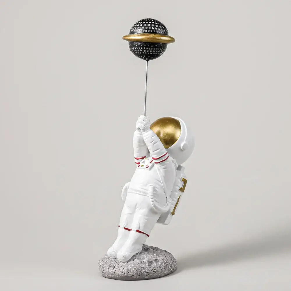 White and gold astronauts figurines holding a black dotted planet balloon for living room decor by decorbites astronauts figurines