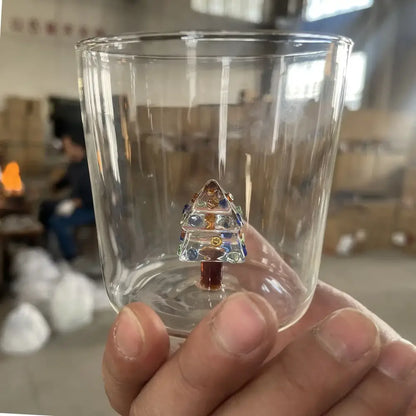 A clear glass 300ml 3d christmas tree wine glass with a colorful miniature christmas tree ornament inside