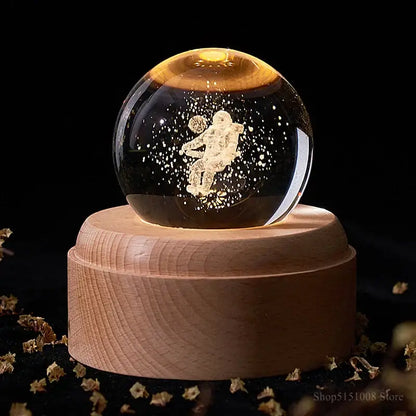 A glowing golden astronaut figurine inside a glass crystal ball night light on a light wooden base decorbites crystal ball