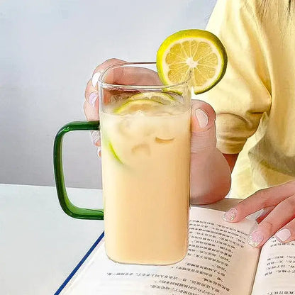 A 400ml square glass mug with vibrant green handle holds iced beverage with lemon slices and bamboo lid and straw