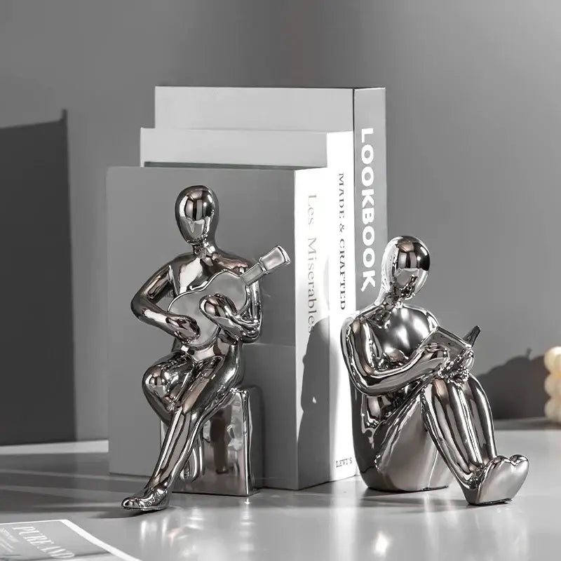Shiny metallic black and gold character bookends shaped as seated figures playing guitar and reading in abstract nordic style decorbites abstract nordic