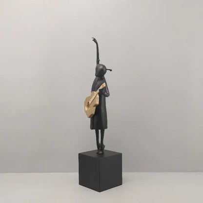 Abstract guitarist resin sculpture in black with gold-accented guitar standing on black cube base for living room decor