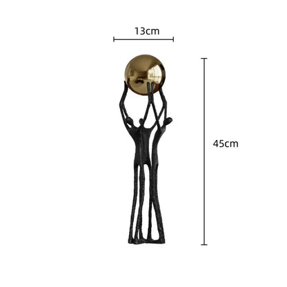 Abstract black and gold human figurine with three forms supporting a polished golden ball holder for living room decor