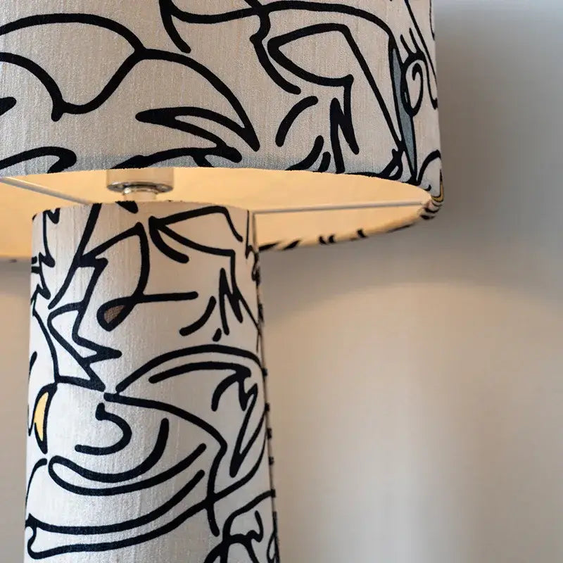 A study lamp with textured fabric base and shade featuring bold black abstract line art for decorbites designer french medieval decor