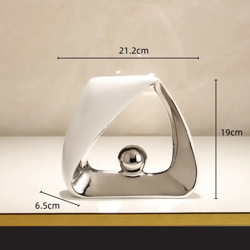 A sleek abstract geometric triangles sculpture with a silver frame and glossy golden ball for modern home decor