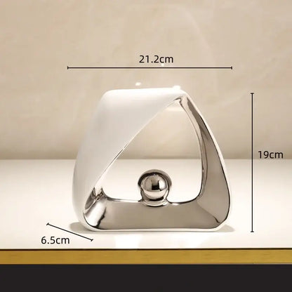 A sleek abstract geometric triangles sculpture with a silver frame and glossy golden ball for modern home decor