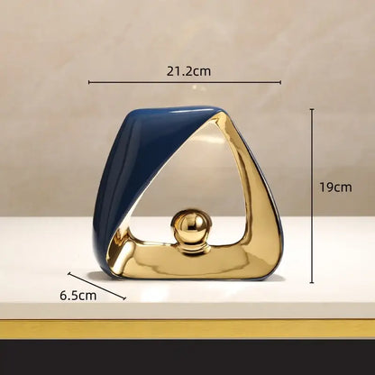 A sleek ceramic geometric triangles sculpture with glossy navy blue and gold finish and a polished golden ball for home decor