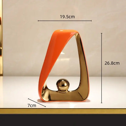 A sleek abstract black and gold geometric triangles sculpture with a glossy golden ball for modern home decor