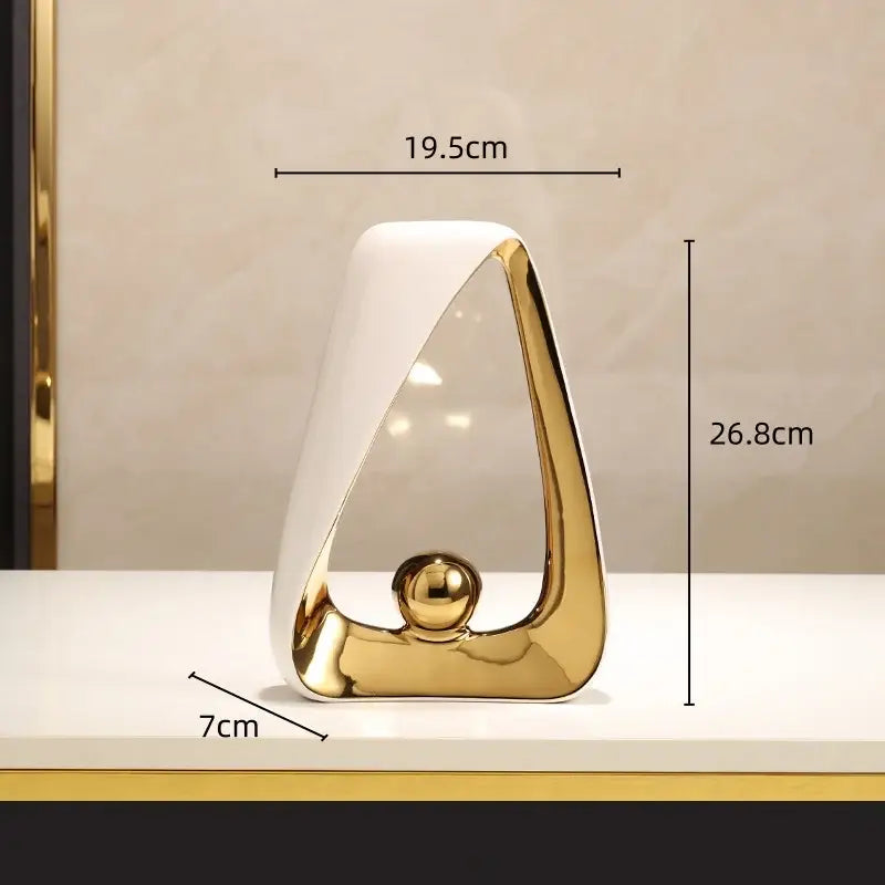 A sleek ceramic geometric triangles sculpture with a glossy white and gold finish featuring a golden ball for home decor