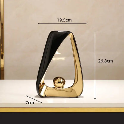 A sleek black and gold abstract geometric triangles sculpture with a golden ball for modern home decor