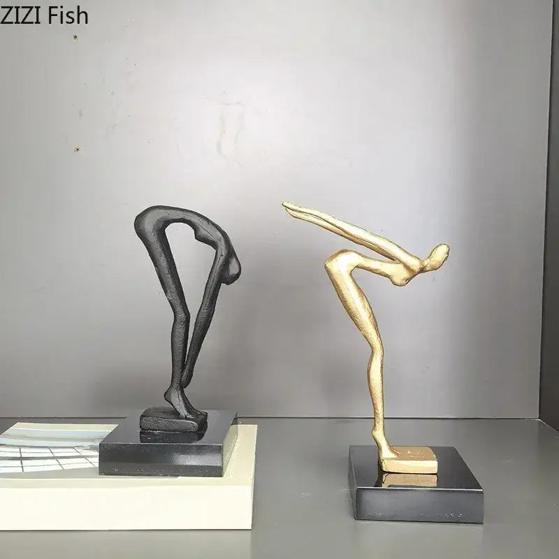 Two abstract gymnast statue desk ornaments in matte black and gold metal on sleek black rectangular bases for decorbites decor