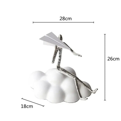 Silver metallic figurine sitting on white resin paper airplane cloud holding paper airplane for living room decor