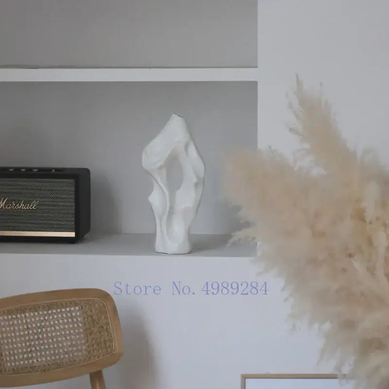 A sleek white abstract ceramic vase with organic form by decorbites black sits elegantly on a shelf for living room decor