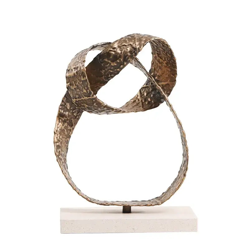 Abstract bronze geometric sphere pendant sculpture with intertwined textured bands on white pedestal for living room decor