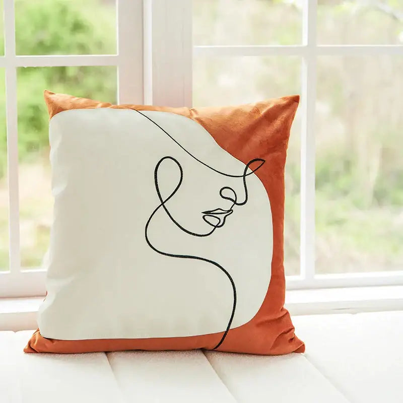 A square pillow cover with burnt orange velvet trim and minimalist black line art face on off-white center panel decorbites abstract plush