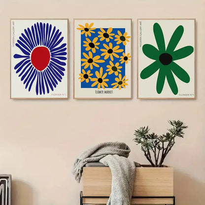 Three framed modern floral flowers wall art prints with bold blue, red, yellow, and green stylized designs on canvas