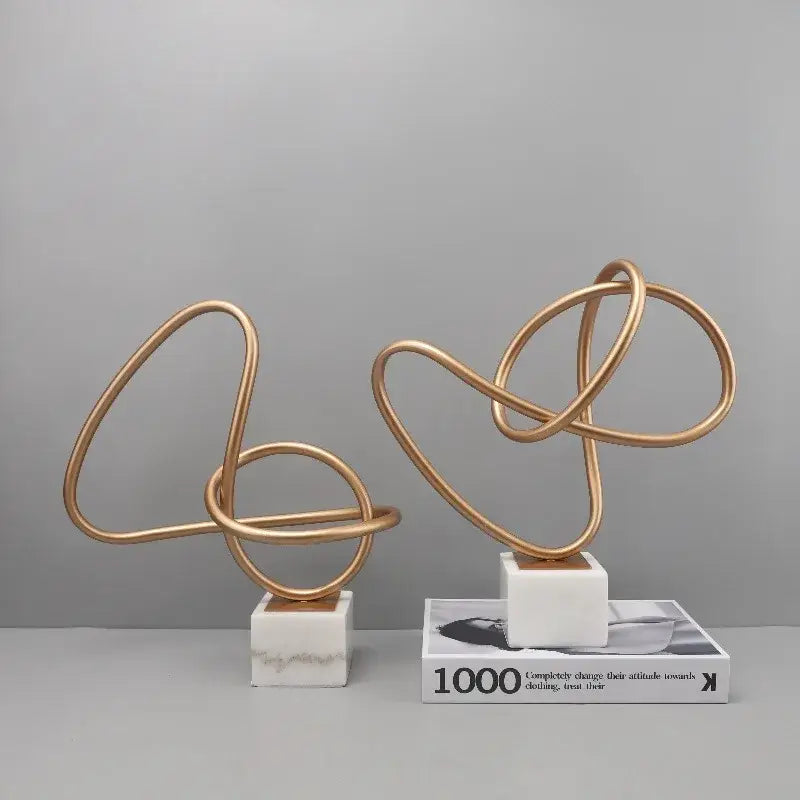 Abstract gold line geometric metal sculptures with intertwined loops on white marble bases for living room decorbites decor