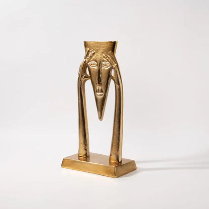 Abstract golden masked figure sculpture with elongated limbs and triangular nose on rectangular base for living room decor