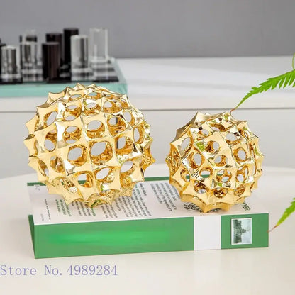 Two golden metal hollow ball spike ornaments with intricate geometric lattice design for living room decor