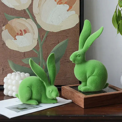 Two vibrant green plush-textured abstract rabbit figurines in seated and crouching poses made of resin decor art