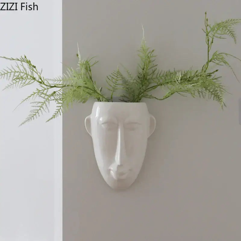 White ceramic vase wall decor featuring an abstract human face planter with green ferns by decorbites abstract human face