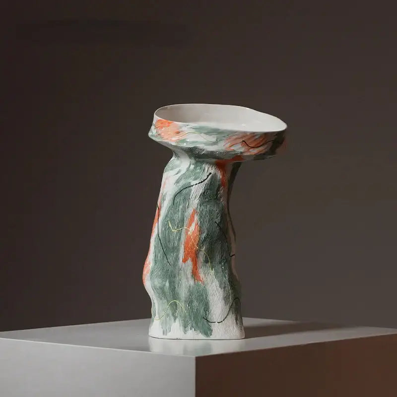 A sculptural ceramic vase with an abstract irregular pattern in green and orange for living room decor