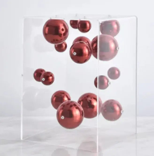 A collection of glossy red abstract metal ball artworks suspended in a transparent acrylic cube decorbites abstract metal decor