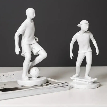 White resin abstract sports player sculpture set featuring two stylized boys with soccer ball and skateboard decorbites abstract sports