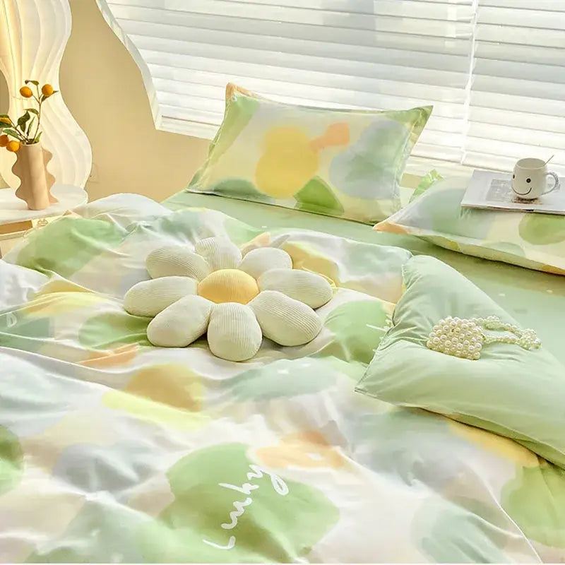 A plush white and yellow flower pillow on a bed with an abstract watercolor pastel green and yellow decorbites cute pattern duvet cover