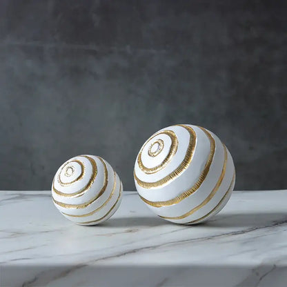 Two white ceramic spheres with golden texture spiral stripes in abstract golden texture ball living room decor