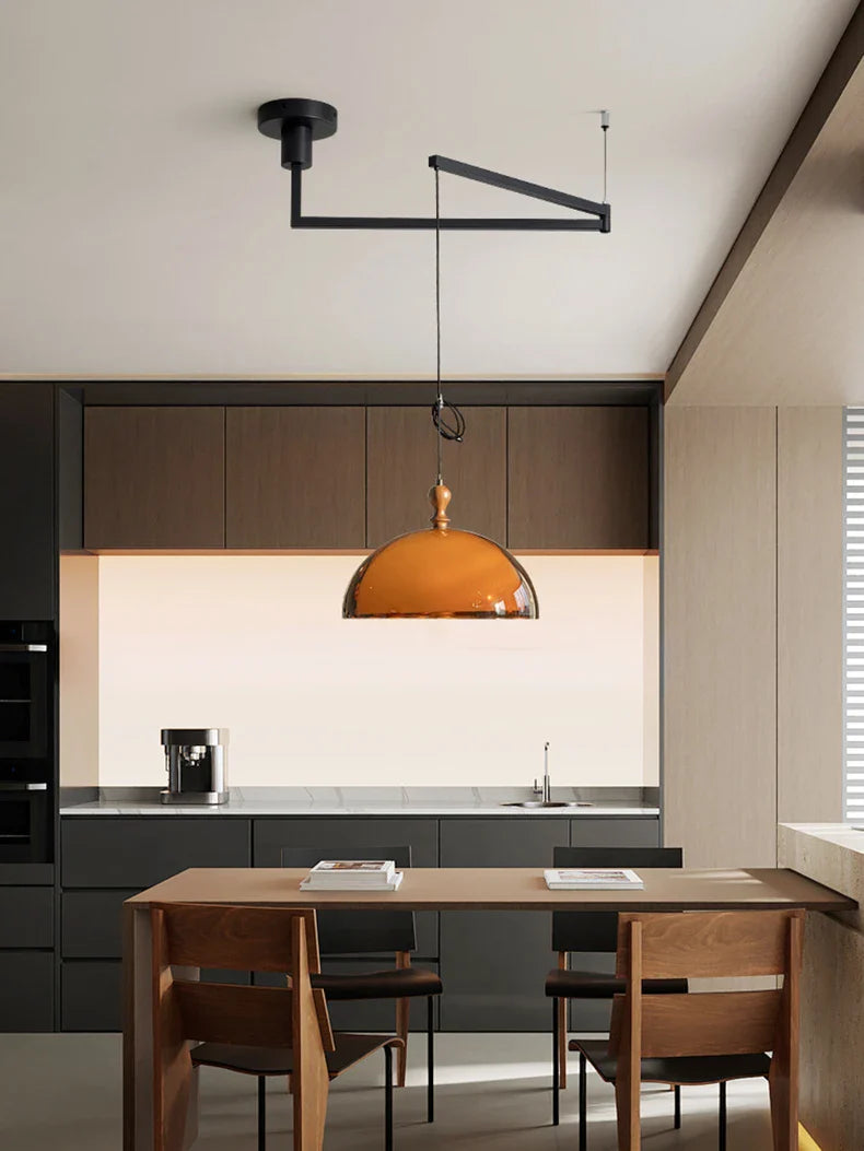 Warm amber glass pendant light with brass top and black metal arm complements acrylic pendant light dark wood lampshade