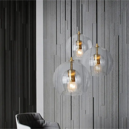 Three modern amber and clear glass pendant lights with brass accents hang as kitchen gold cord pendant lights