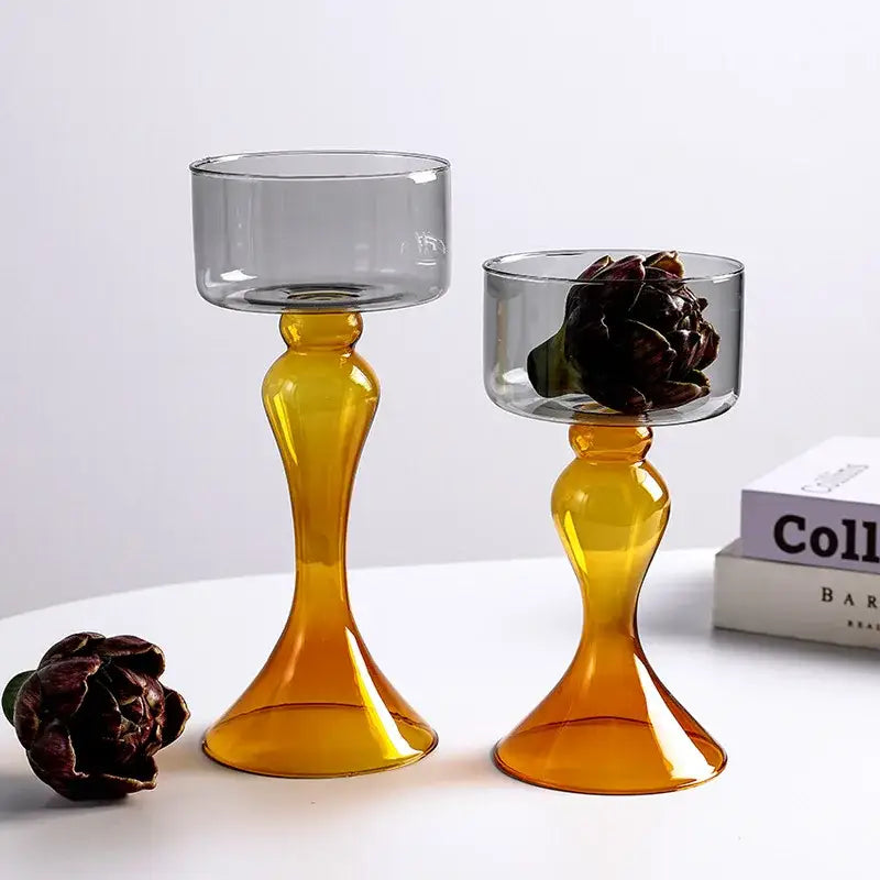 Two translucent amber decorbites geometric glass candle holders with flared base, one holding a dark dried flower